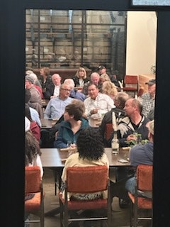 A group of people dining in a busy restaurant with a bookshelf in the background.