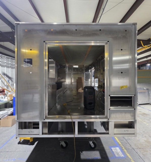 The image shows the interior of a metal trailer or structure, likely for commercial use, with unfinished walls and partitions.