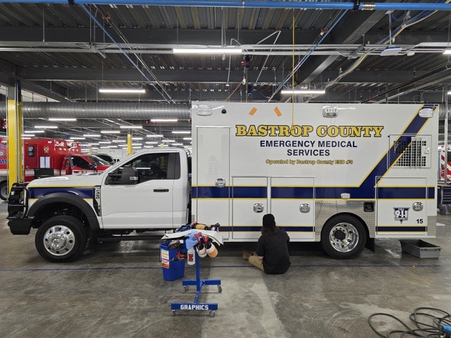 A Bastrop County emergency medical services vehicle is being worked on inside a garage.