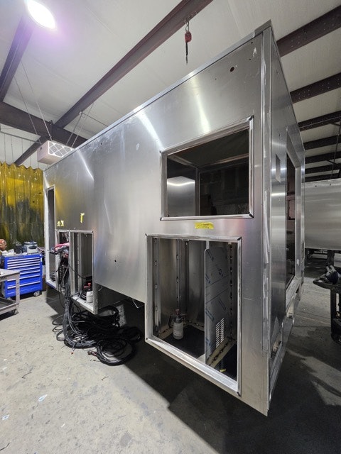 The image shows a partially constructed stainless steel structure, likely a food truck or kiosk, in a workshop.