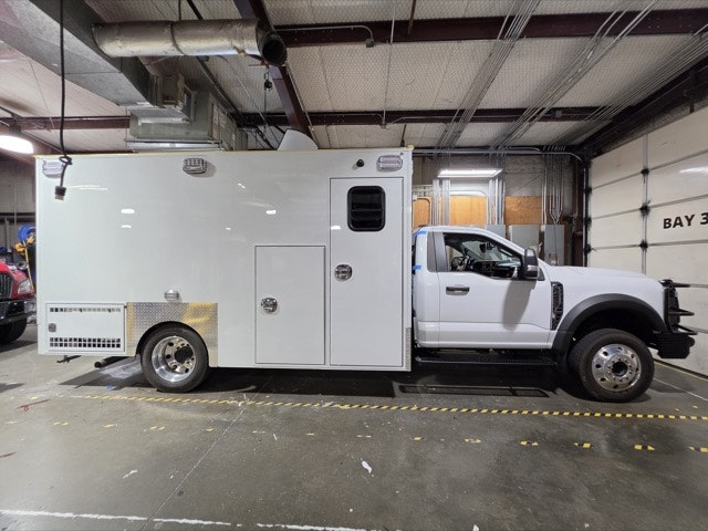 A white truck with a boxy cargo area is parked indoors, possibly used for service or utility purposes.
