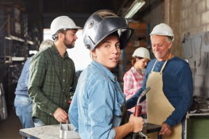 A group of workers in protective gear inside a workshop or factory.