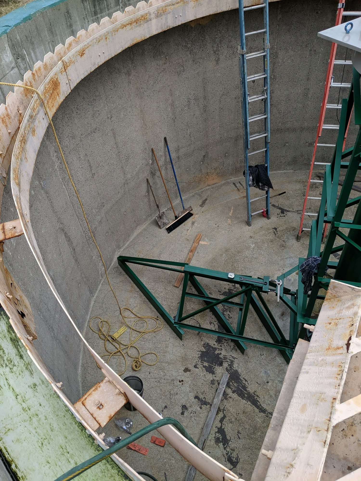 Concrete silo interior with ladder, construction bracing, and tools.