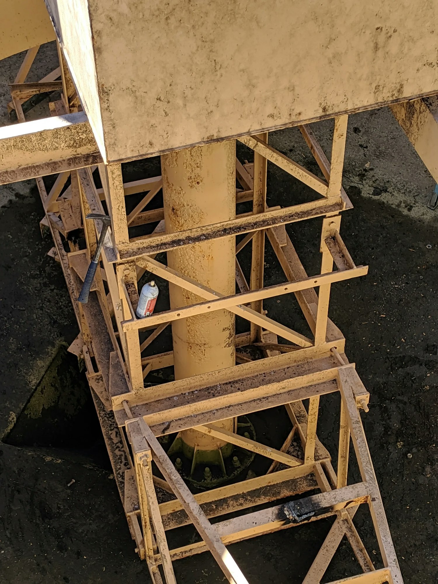 Rusty steel support structure with wooden braces and a discarded beverage can.