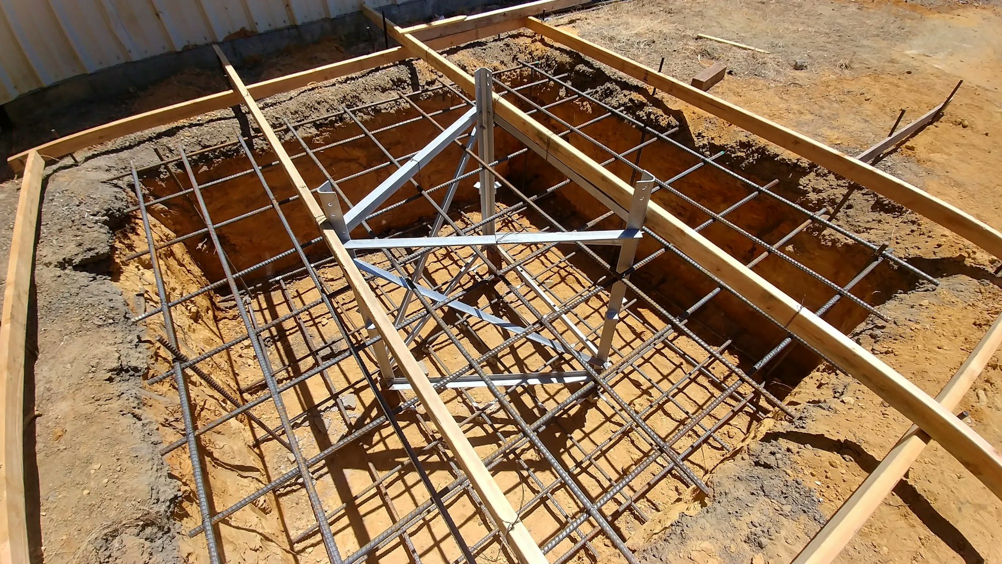 Foundation framework with rebar and wooden forms for concrete pouring at a construction site.