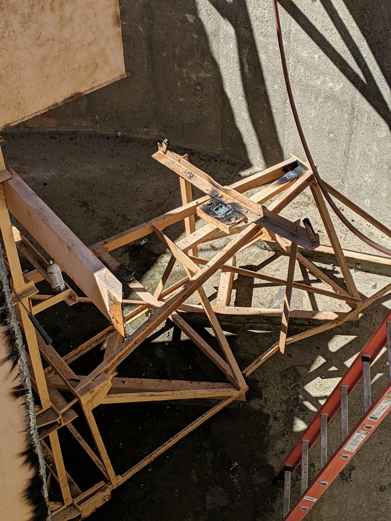 Wooden beams and construction debris in a shadow-cast area, with a ladder partially visible.