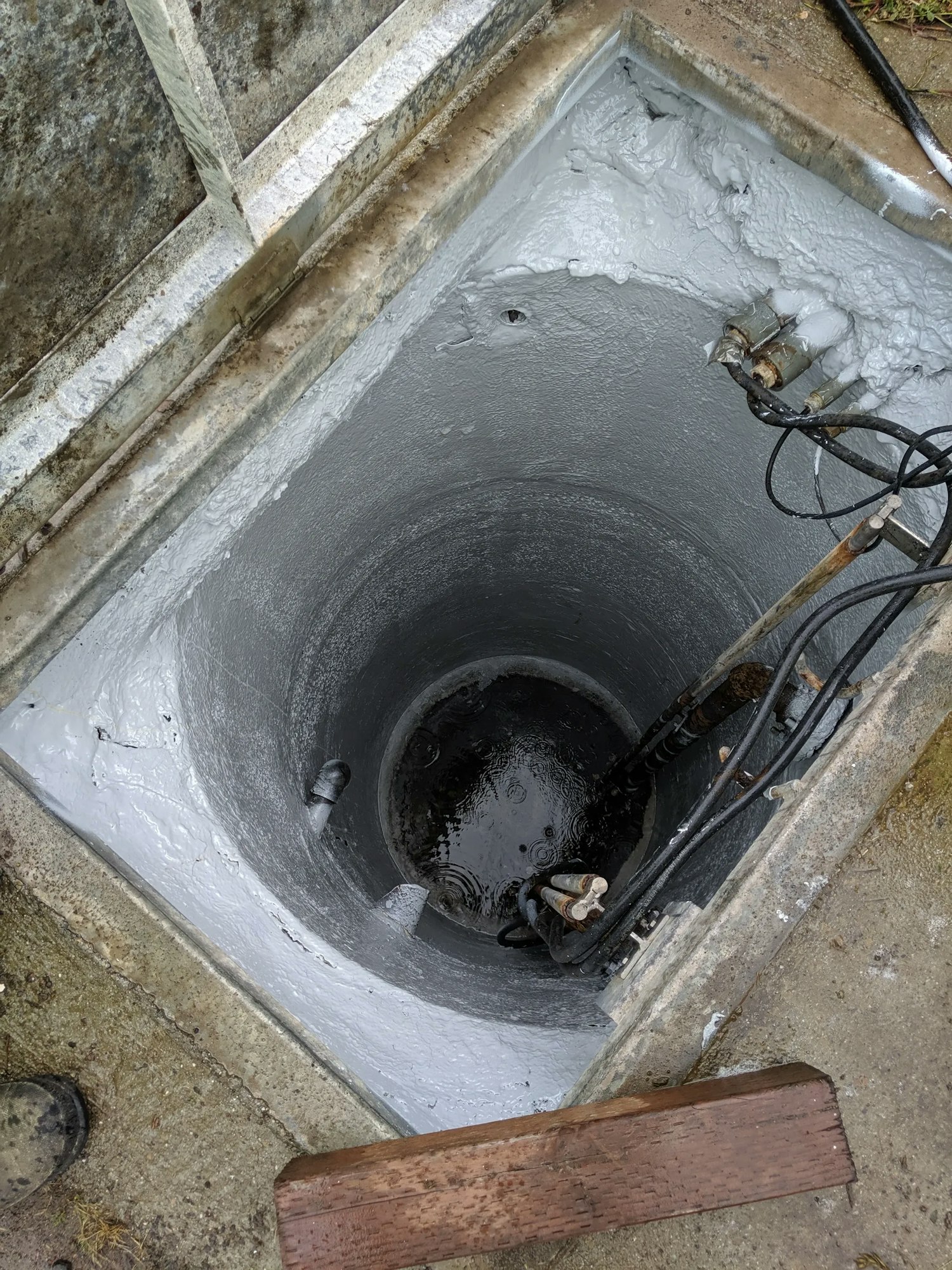 A freshly cemented well with water pipes, surrounded by a concrete frame.