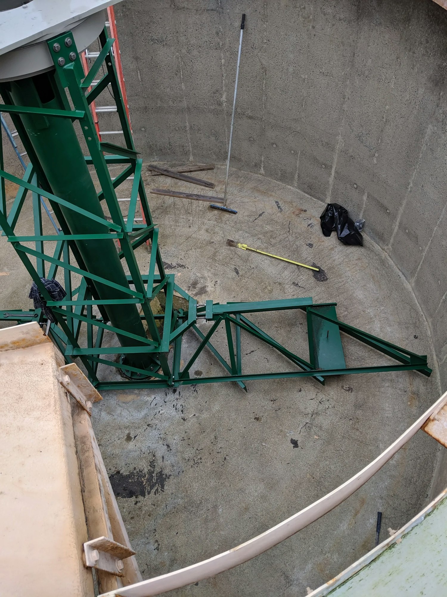 Construction tools and metal framework inside a concrete silo under assembly or repair.