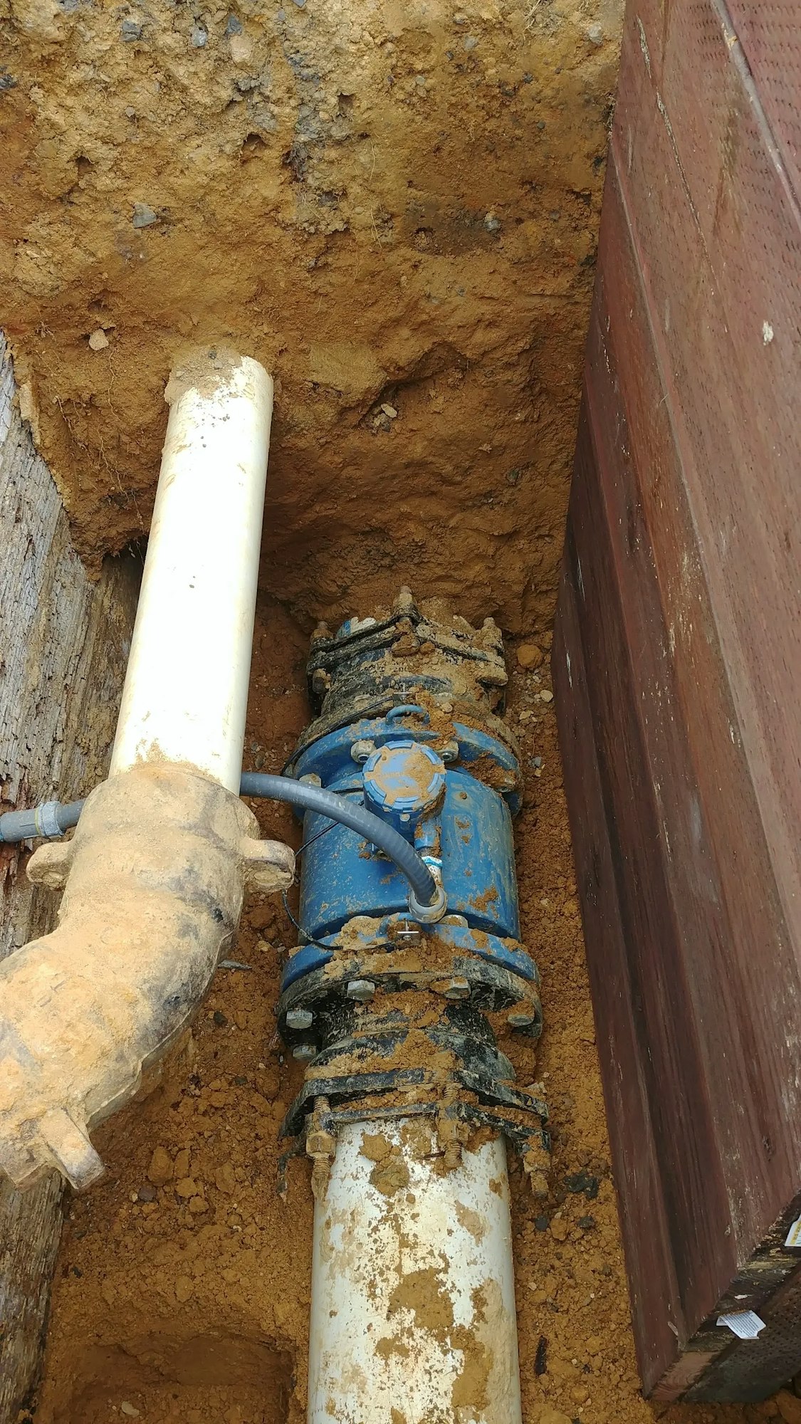 A dug-up ground showing pipes and a blue valve, possibly for water supply.