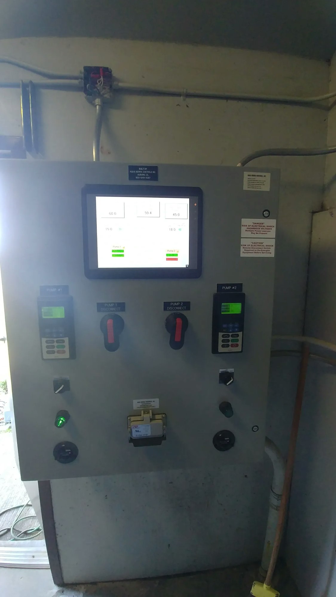 An industrial electrical control panel with gauges, switches, and an LCD screen displaying readings.
