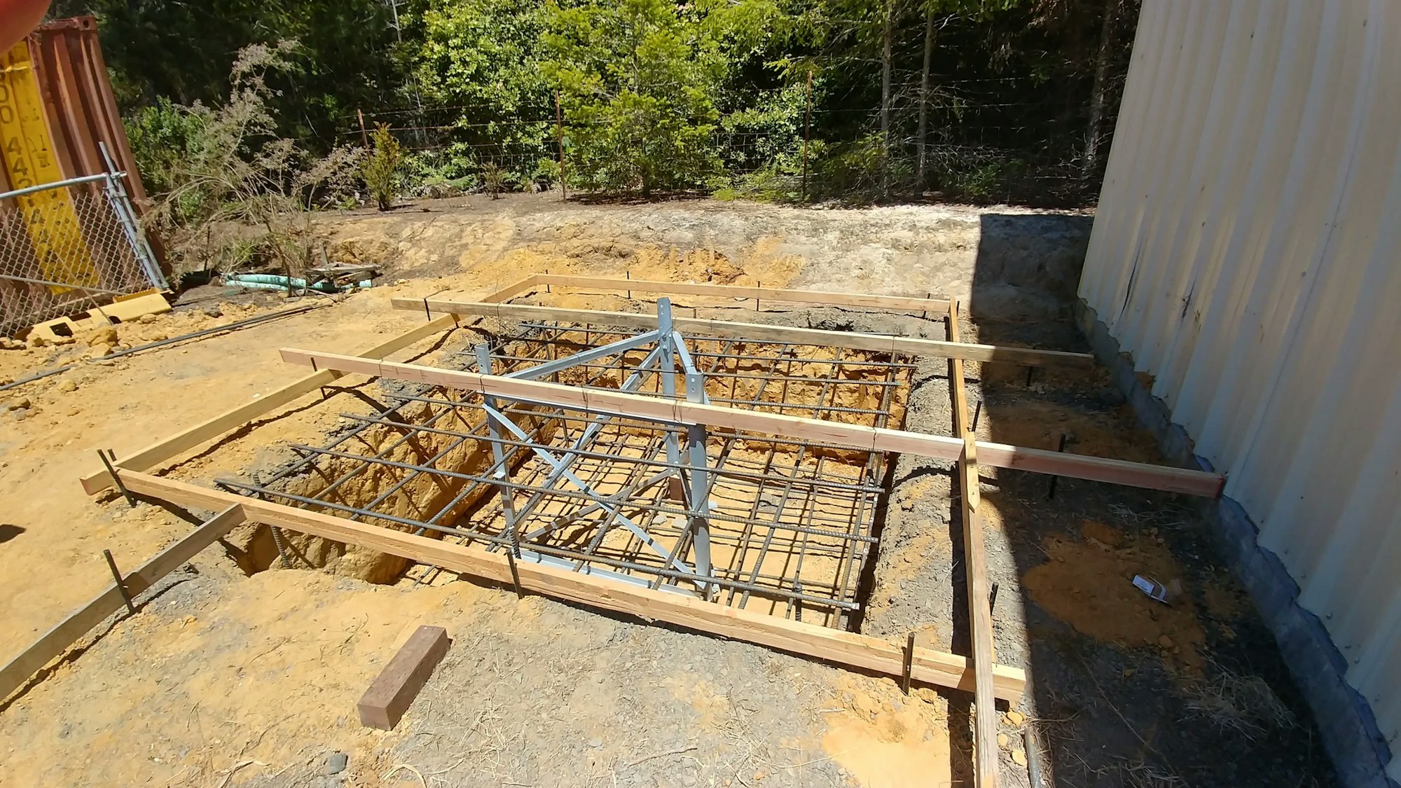 A construction site with wooden formwork and steel rebar for a concrete foundation.