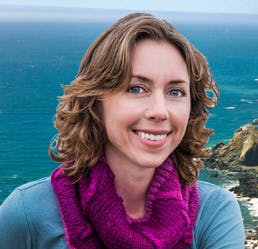 The image features a woman with curly hair wearing a purple scarf, smiling against a scenic coastal backdrop.