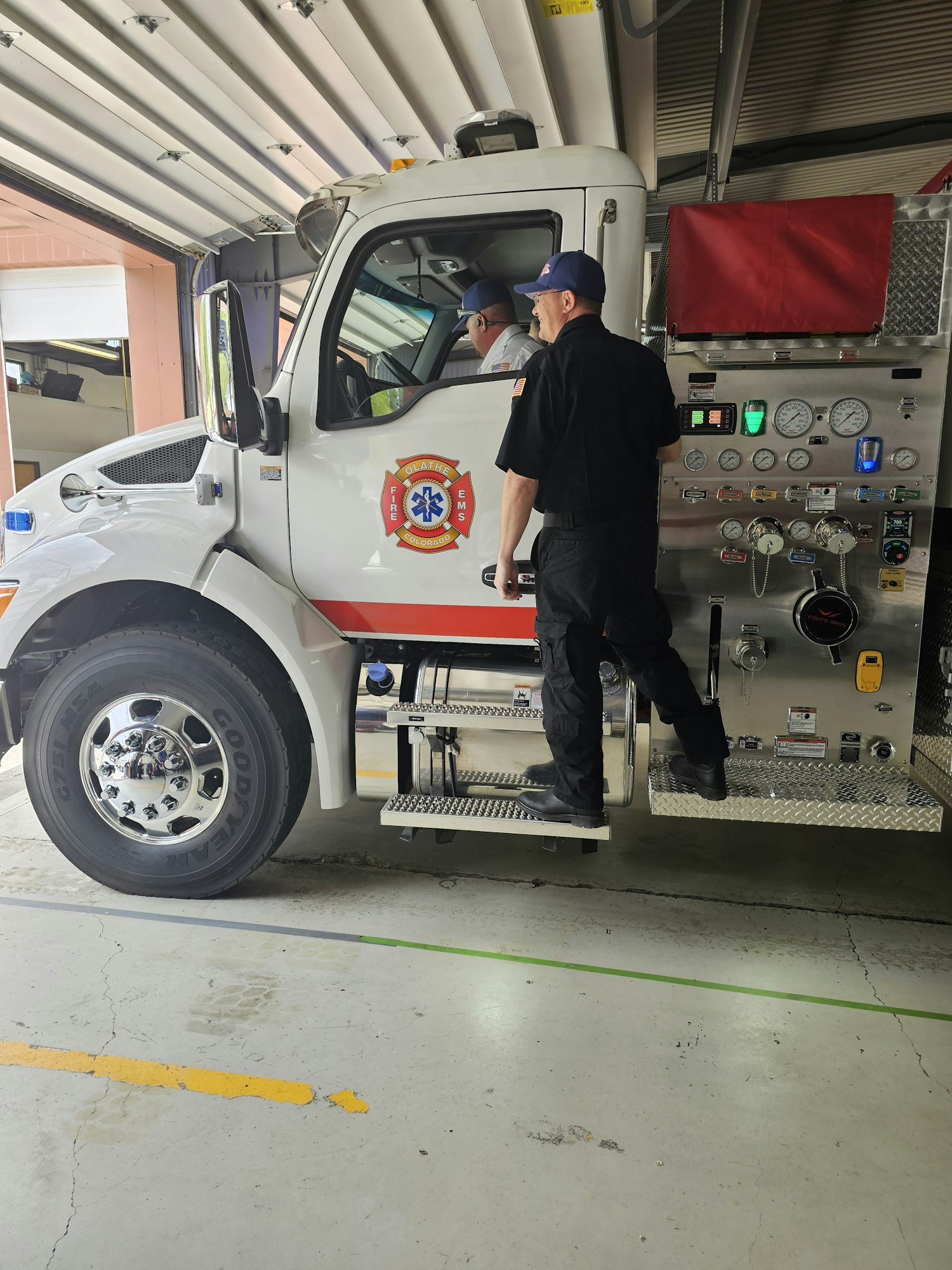 A firefighter leaning into a fire truck, with the truck parked indoors. (Image is rotated 90 degrees)