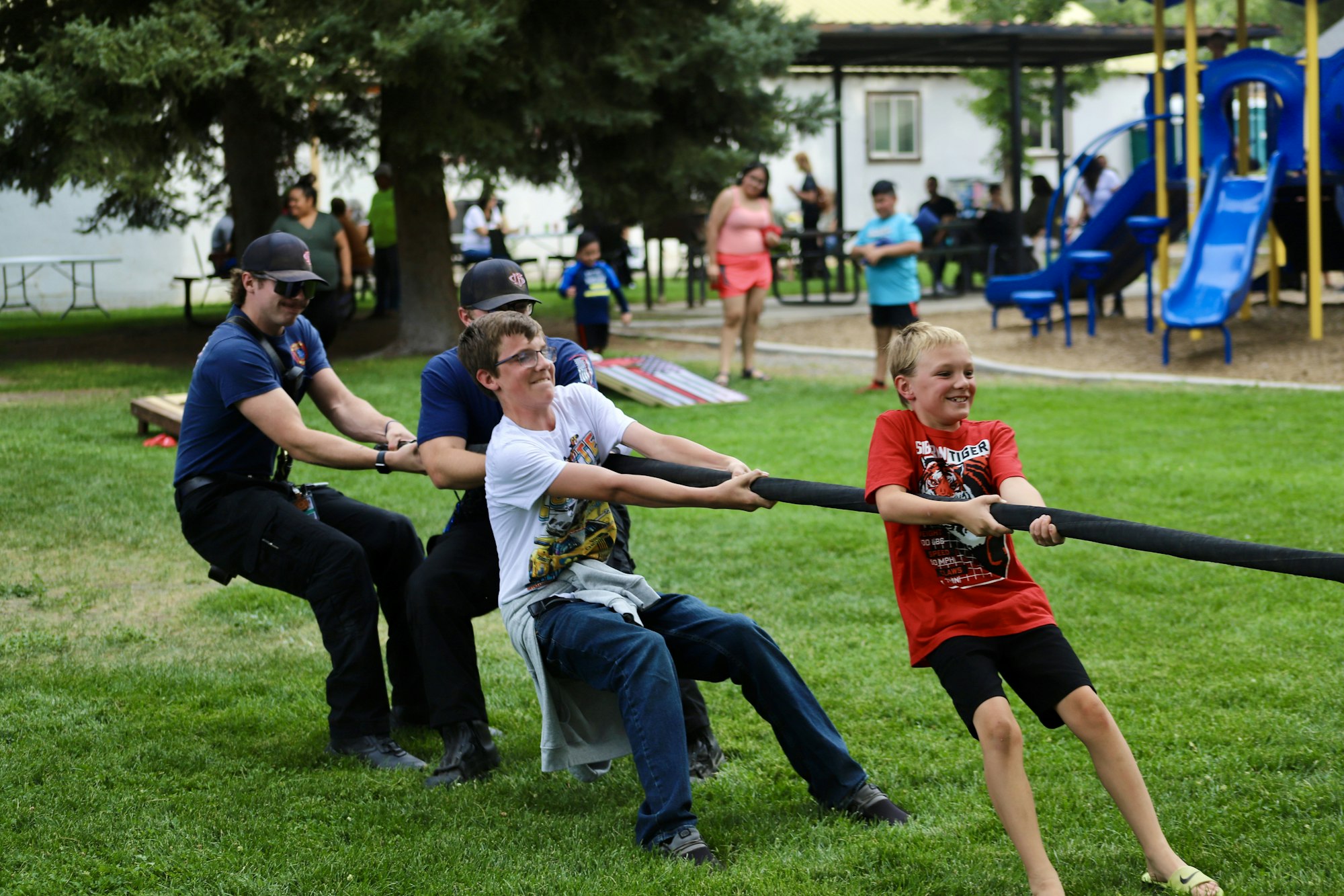 People engaged in a tug of war game at a park.
