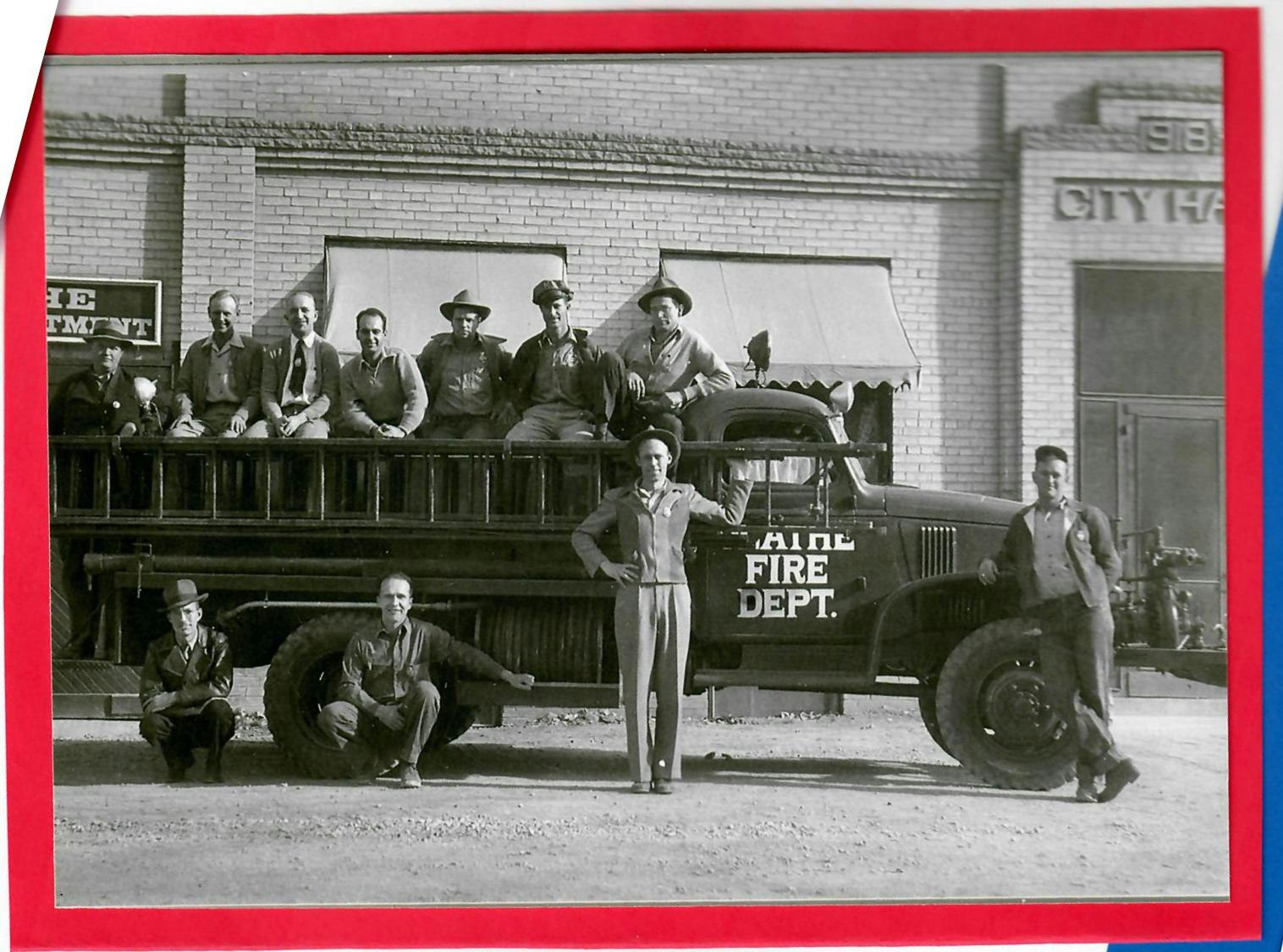 Vintage photo of firefighters with an old fire engine in front of a building marked "CITY HALL."