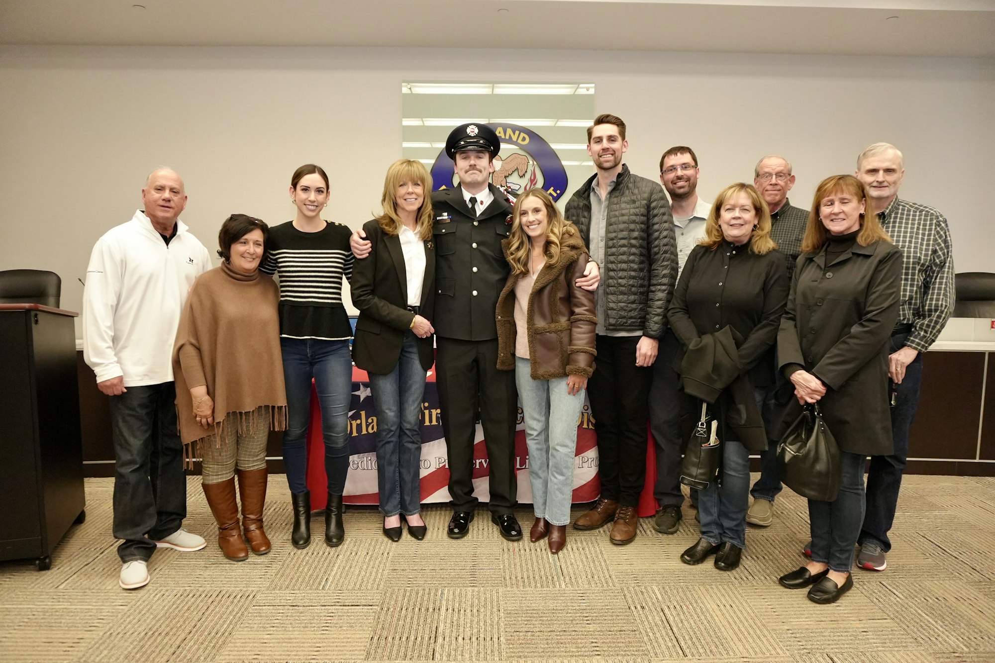 A group of people posing with a person in a uniform in front of a banner indoors.