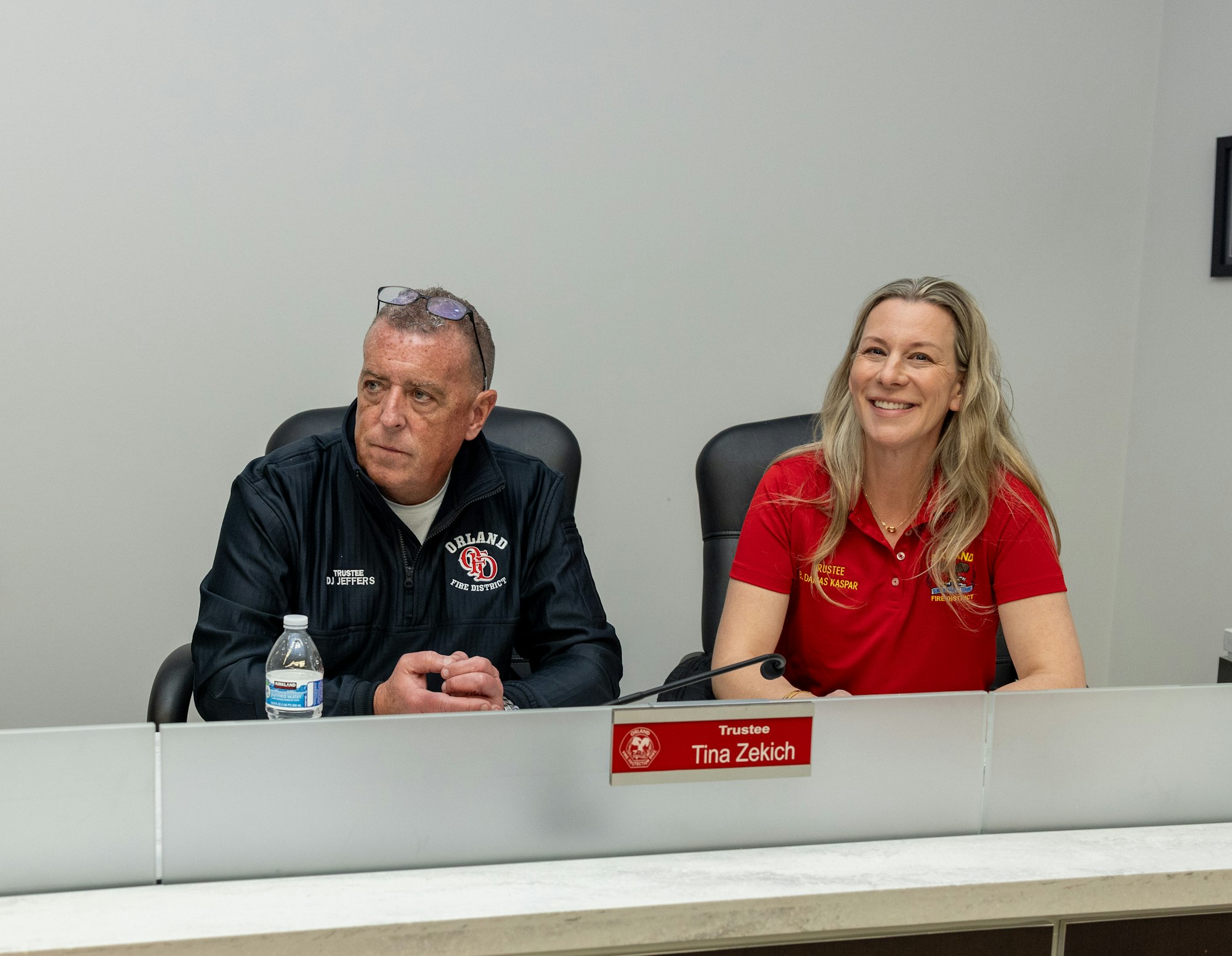 A meeting setting featuring two trustees, one in a black jacket and the other in a red shirt, appearing engaged in discussion.