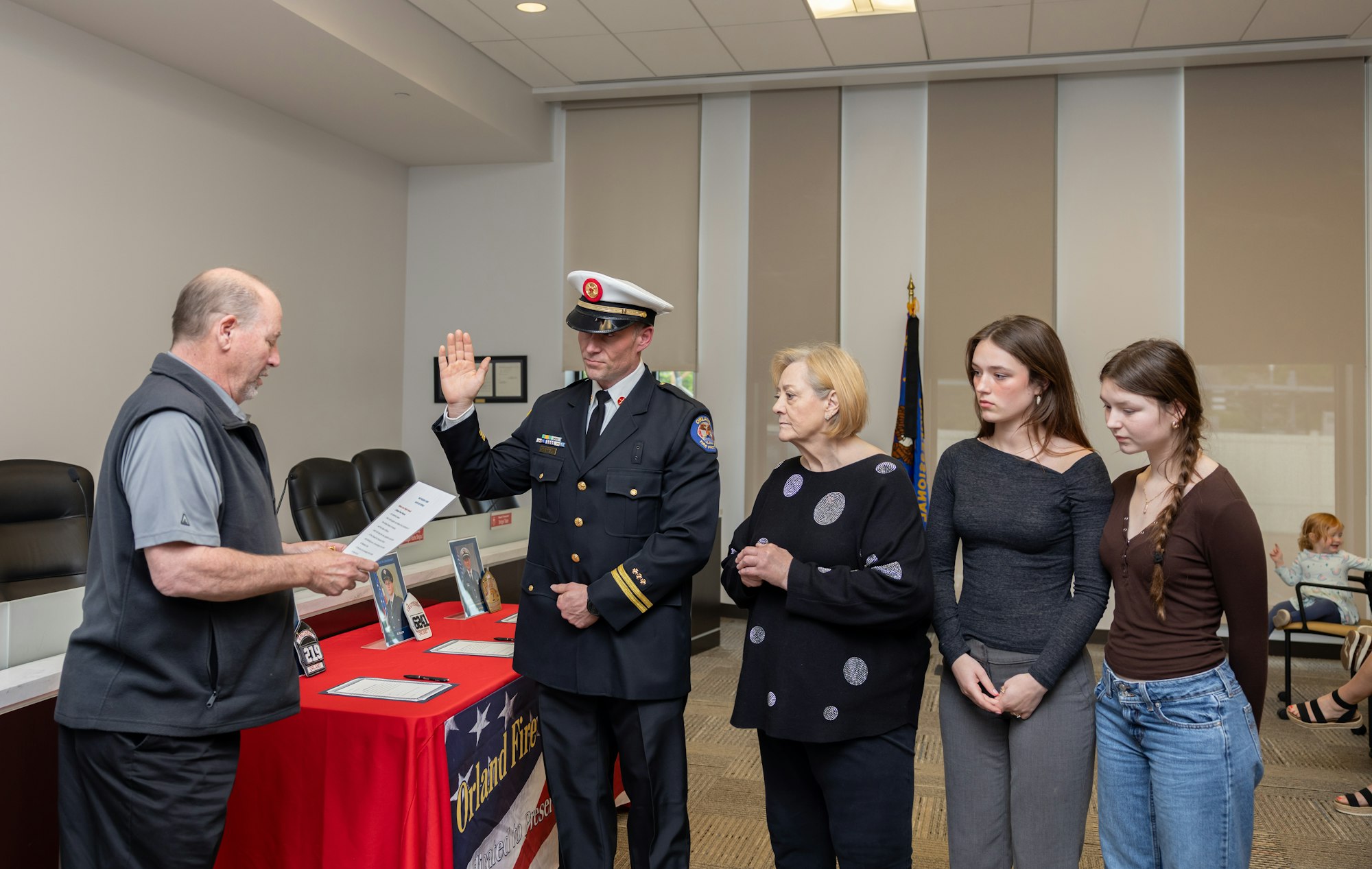 A formal swearing-in ceremony with a new officer being sworn in, accompanied by family members and others in attendance.