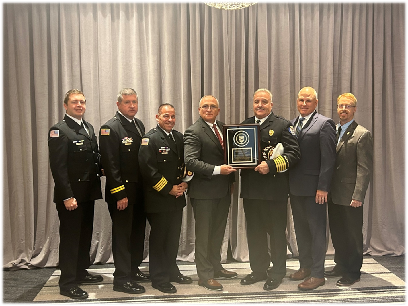 A group of uniformed men holding an award plaque.