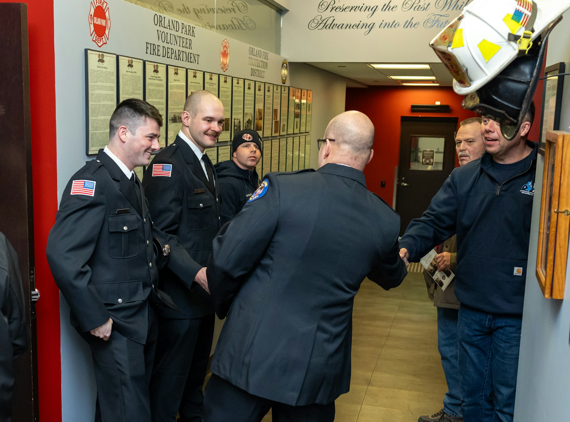 A group of firefighters in uniform greet visitors at the Orland Park Volunteer Fire Department, showcasing community engagement.