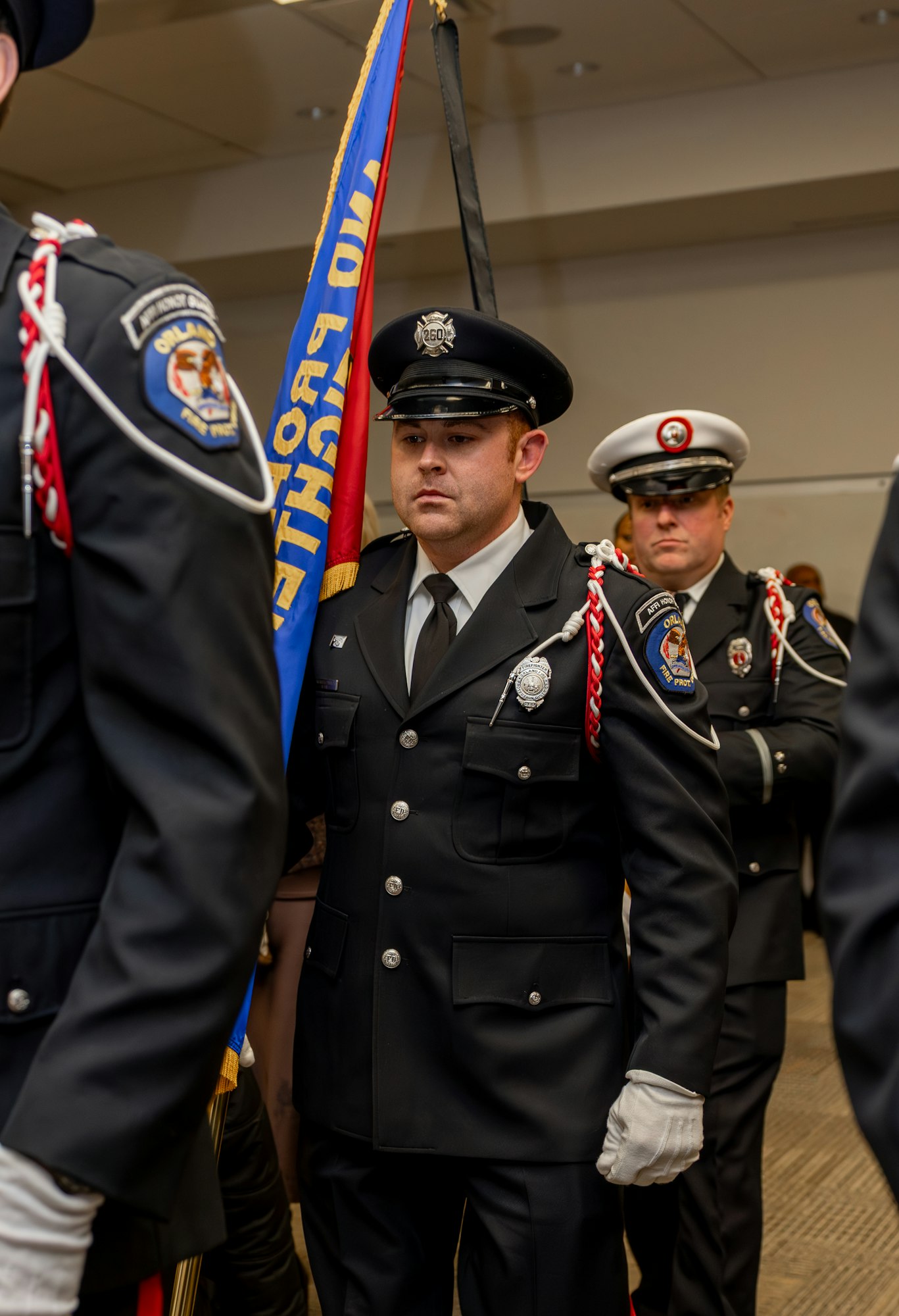 The image shows uniformed officers in a ceremonial setting, one holding a flag, showcasing respect and dedication.
