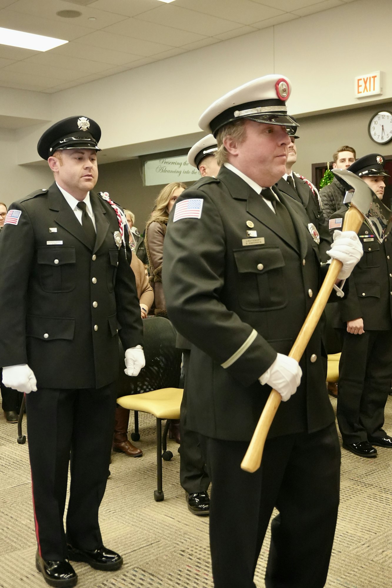 Men in uniform standing indoors; one holds a ceremonial axe.