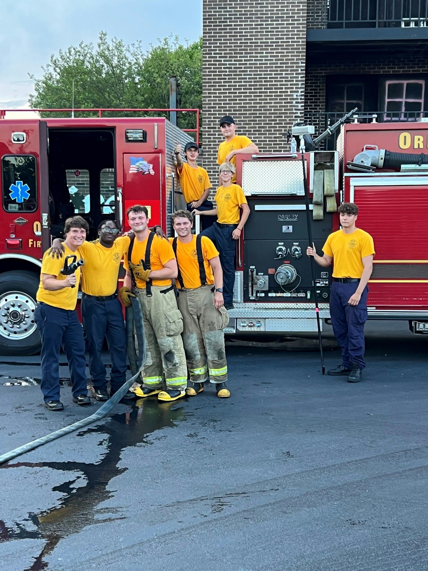 A group of firefighters posing with a fire engine.
