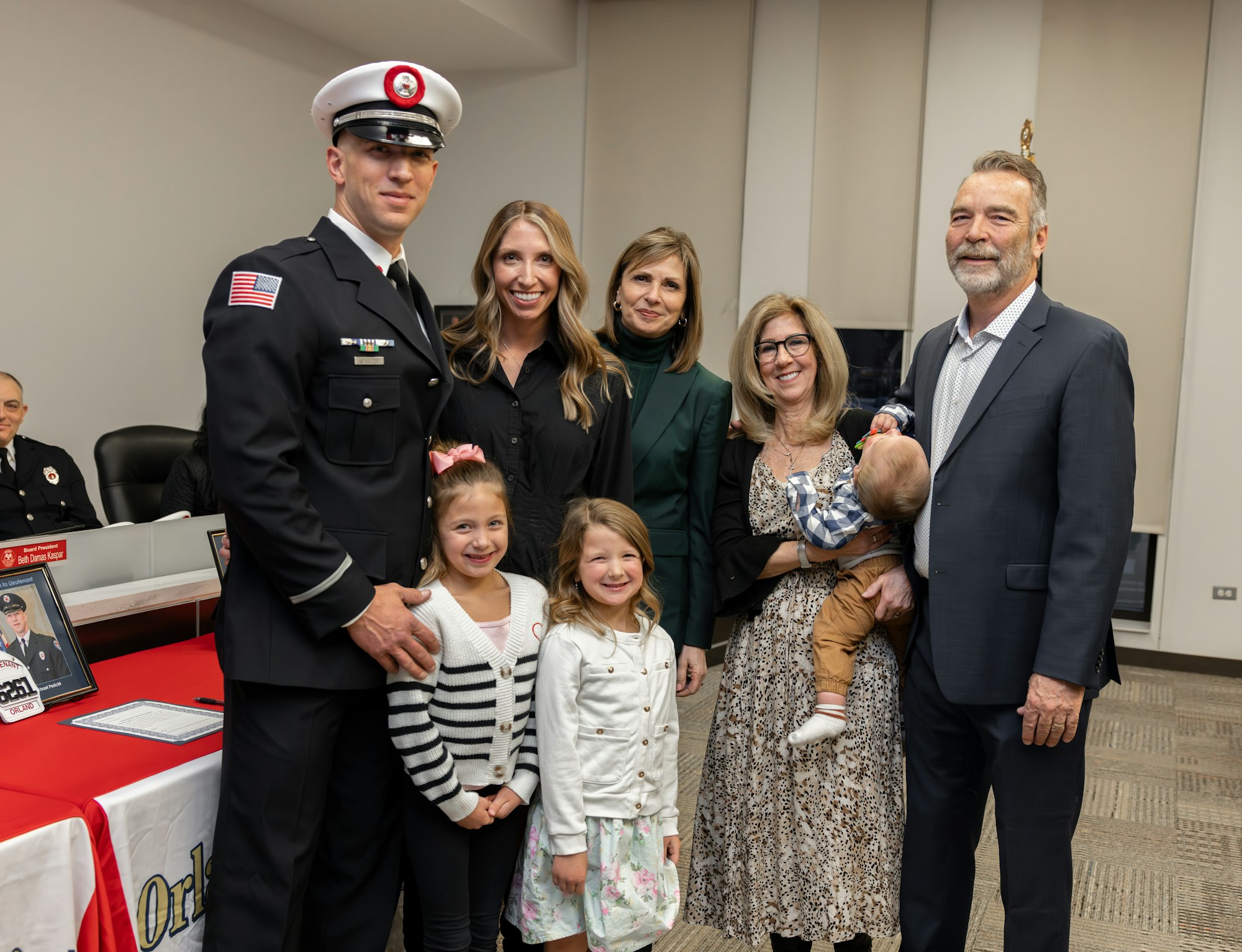 A group portrait featuring a firefighter in uniform with family members, celebrating an occasion, possibly a promotion or graduation.