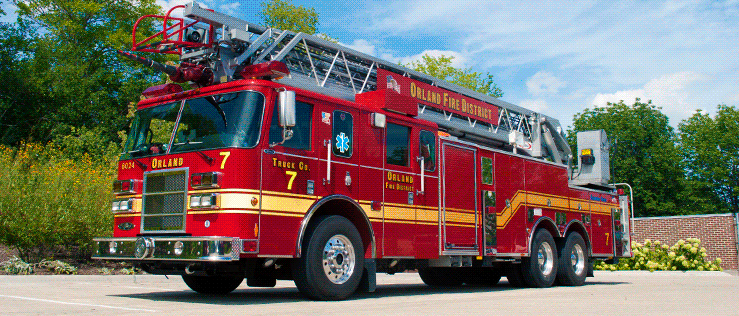 Red fire truck with a ladder from the Orland Fire District, parked outside on a sunny day.