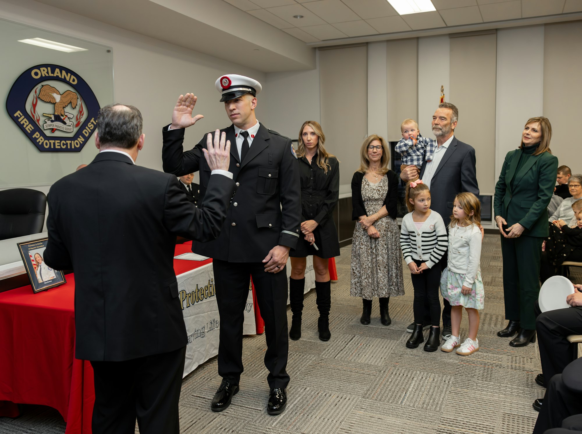 A firefighter is being sworn in, surrounded by family and officials, at a ceremony in the Orland Fire Protection District.