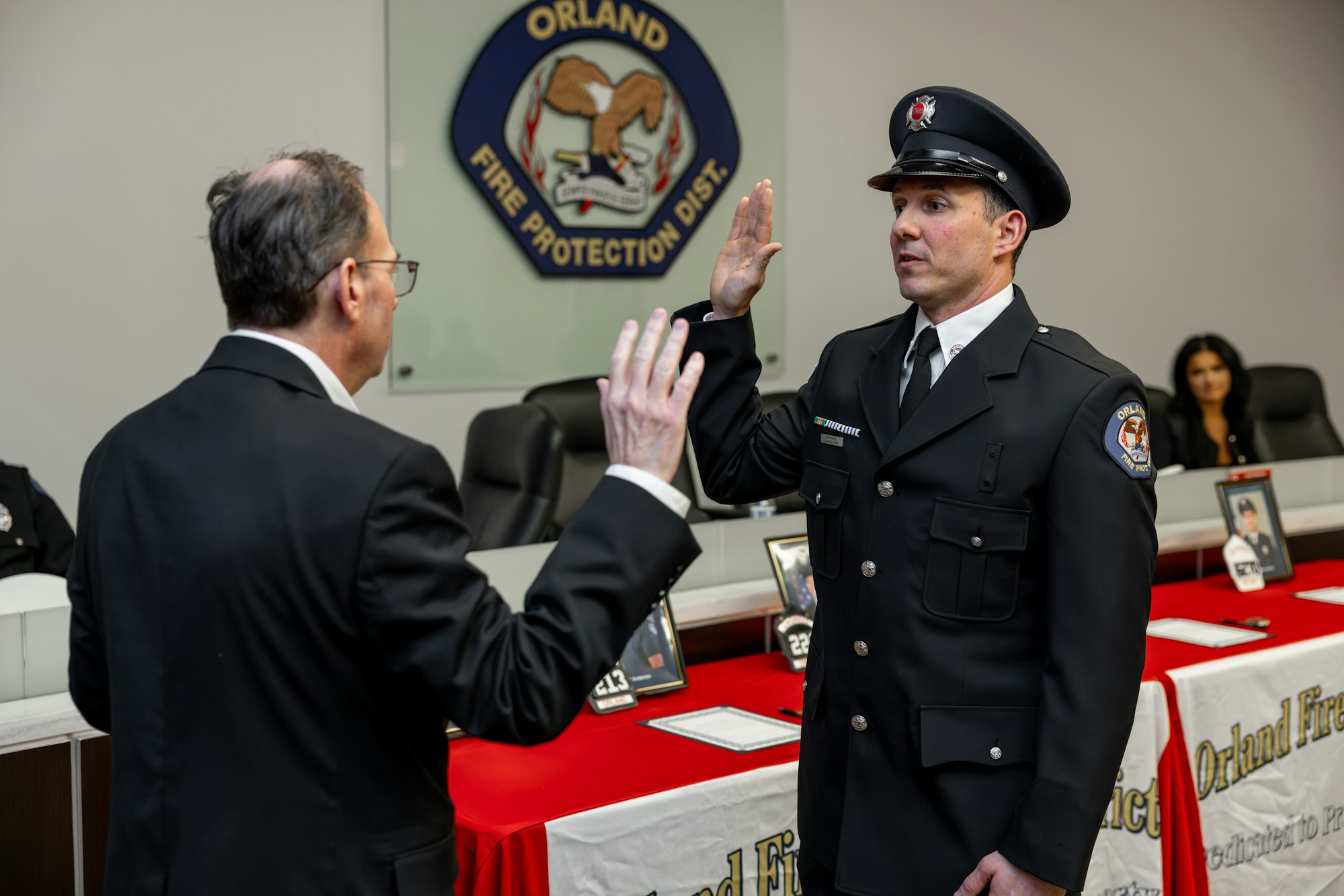 A ceremony where a firefighter is being sworn in, with officials and a backdrop displaying the fire protection district logo.