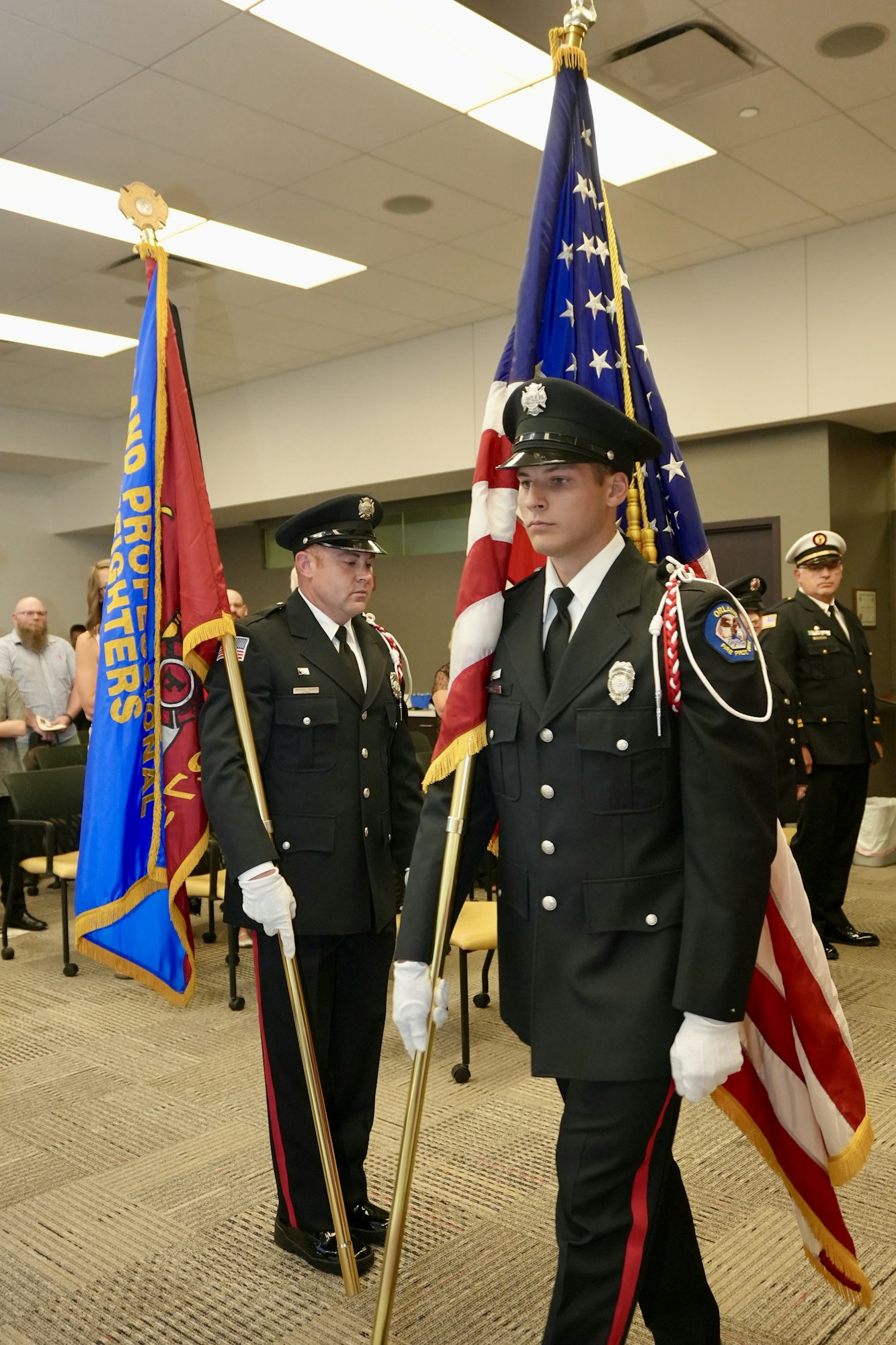 Uniformed men holding flags in a ceremonial setting.