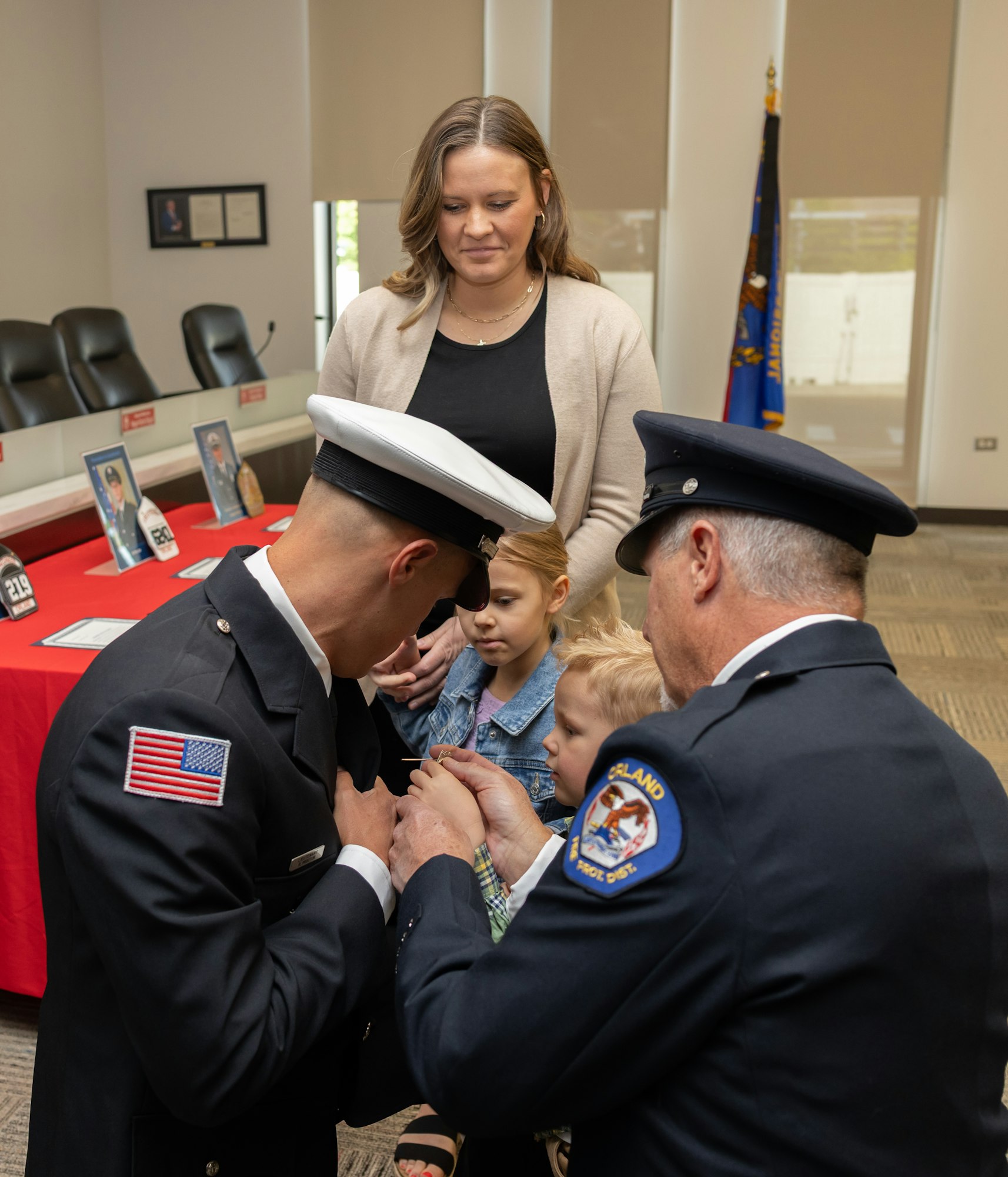 A ceremony where firefighters receive pins or badges, accompanied by family members, signifying recognition or promotion.
