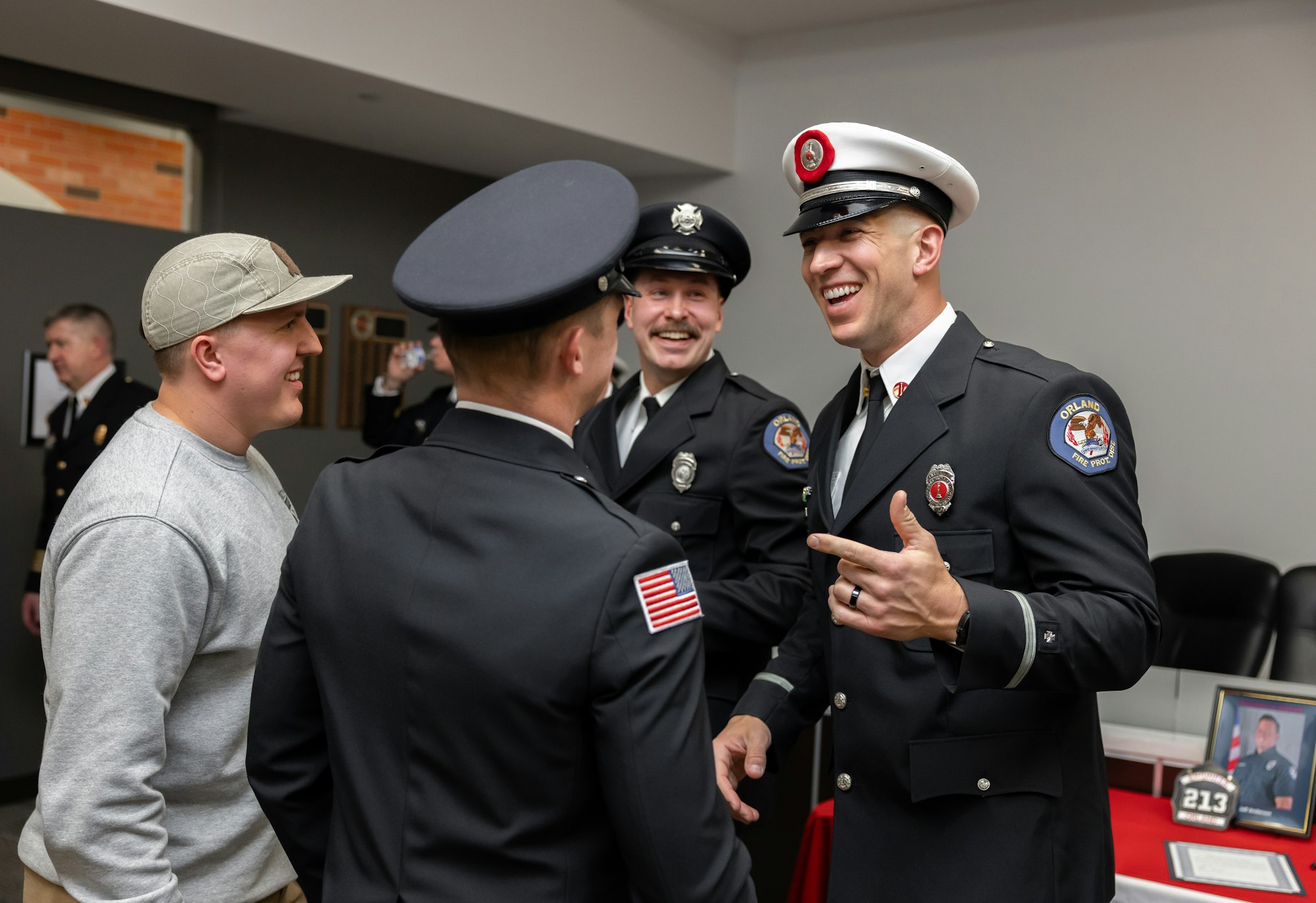 A group of smiling individuals in uniforms chatting and enjoying a moment together, likely at a formal event or ceremony.