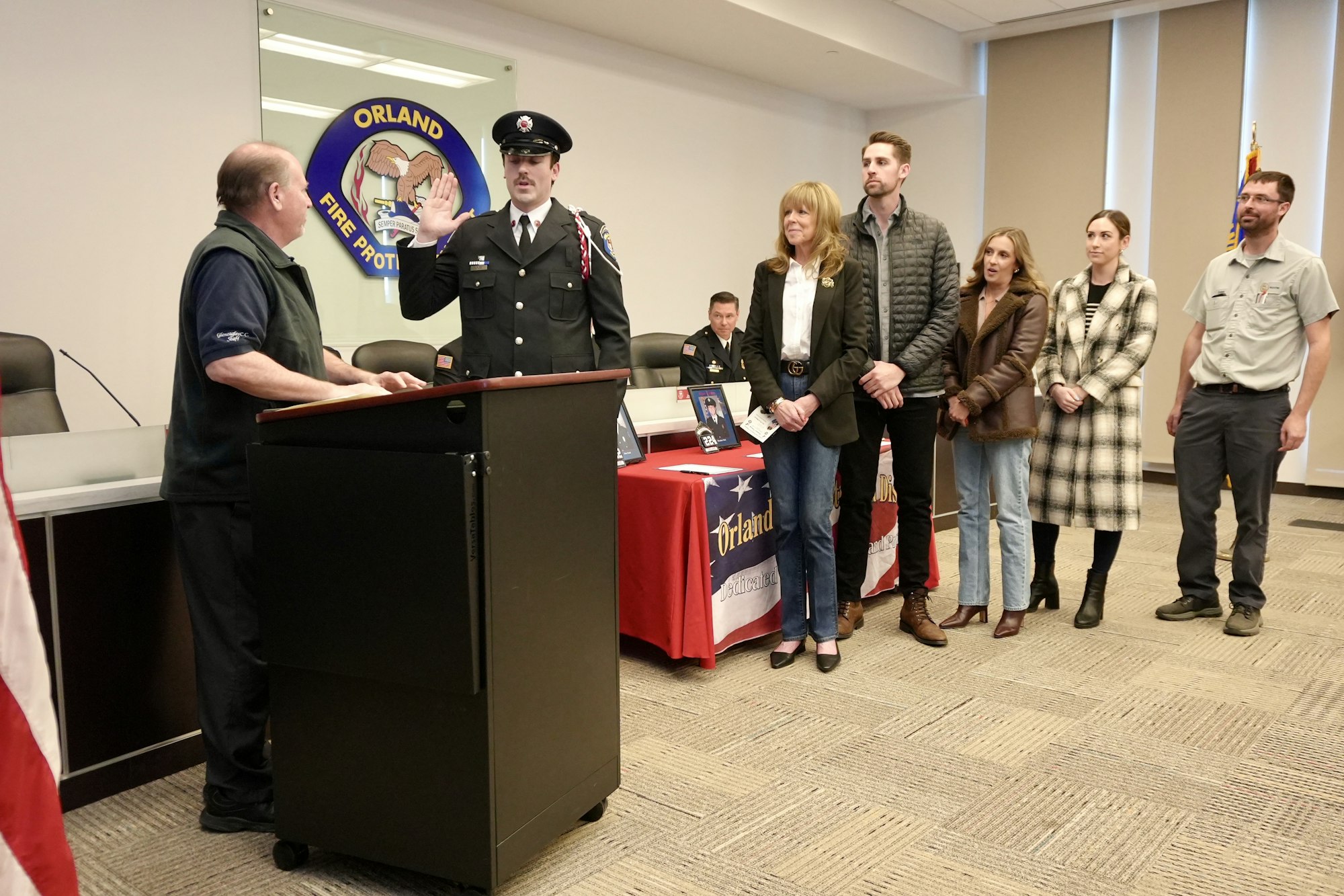 A person in a firefighter uniform is being sworn in, with several people standing by in support.