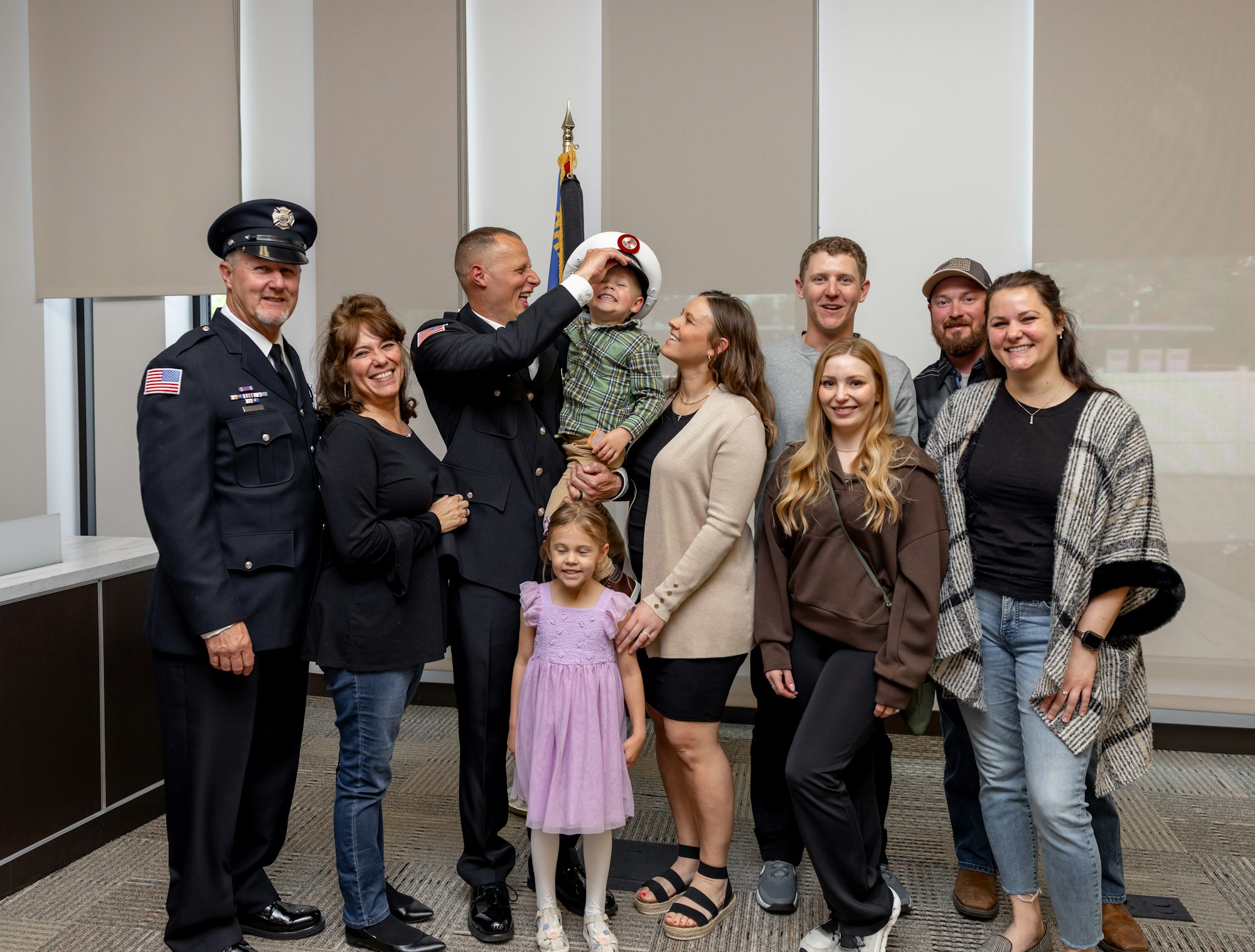 A group of people, including uniformed personnel and family members, celebrate a special occasion, likely a promotion or ceremony.