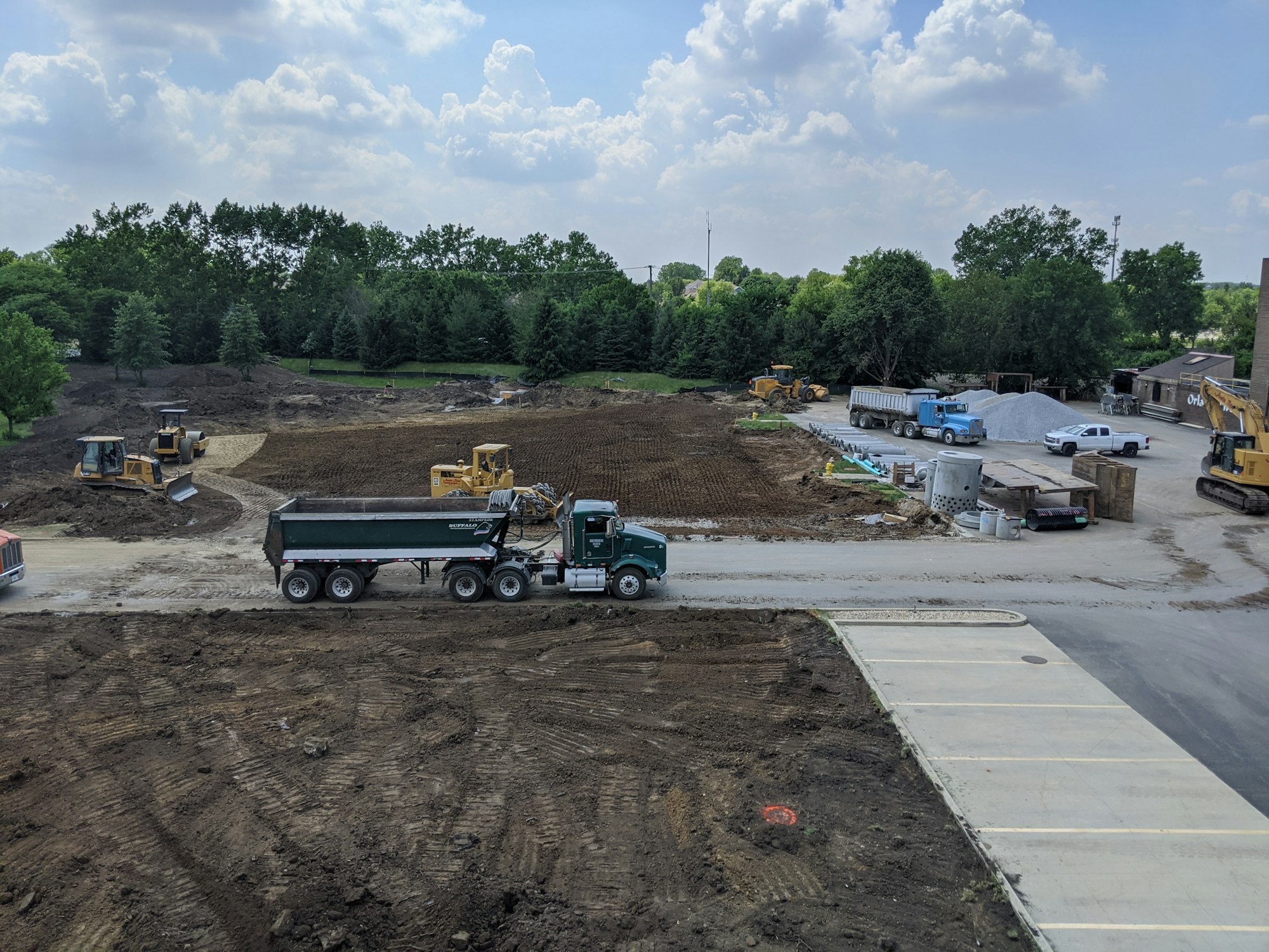 Construction site with earth-moving equipment and trucks.