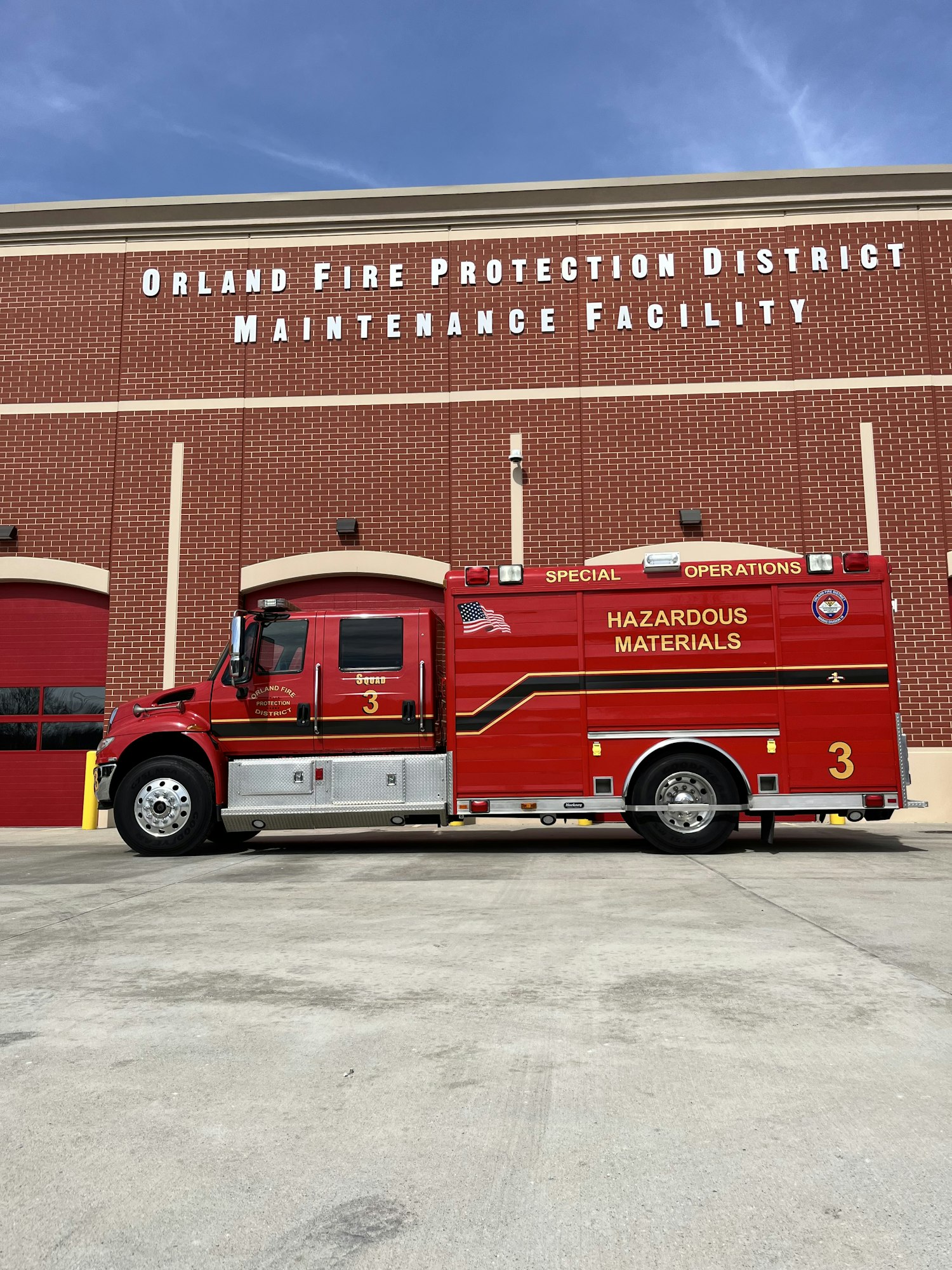 A red fire protection truck labeled for hazardous materials parked outside the Orland Fire Protection District maintenance facility.