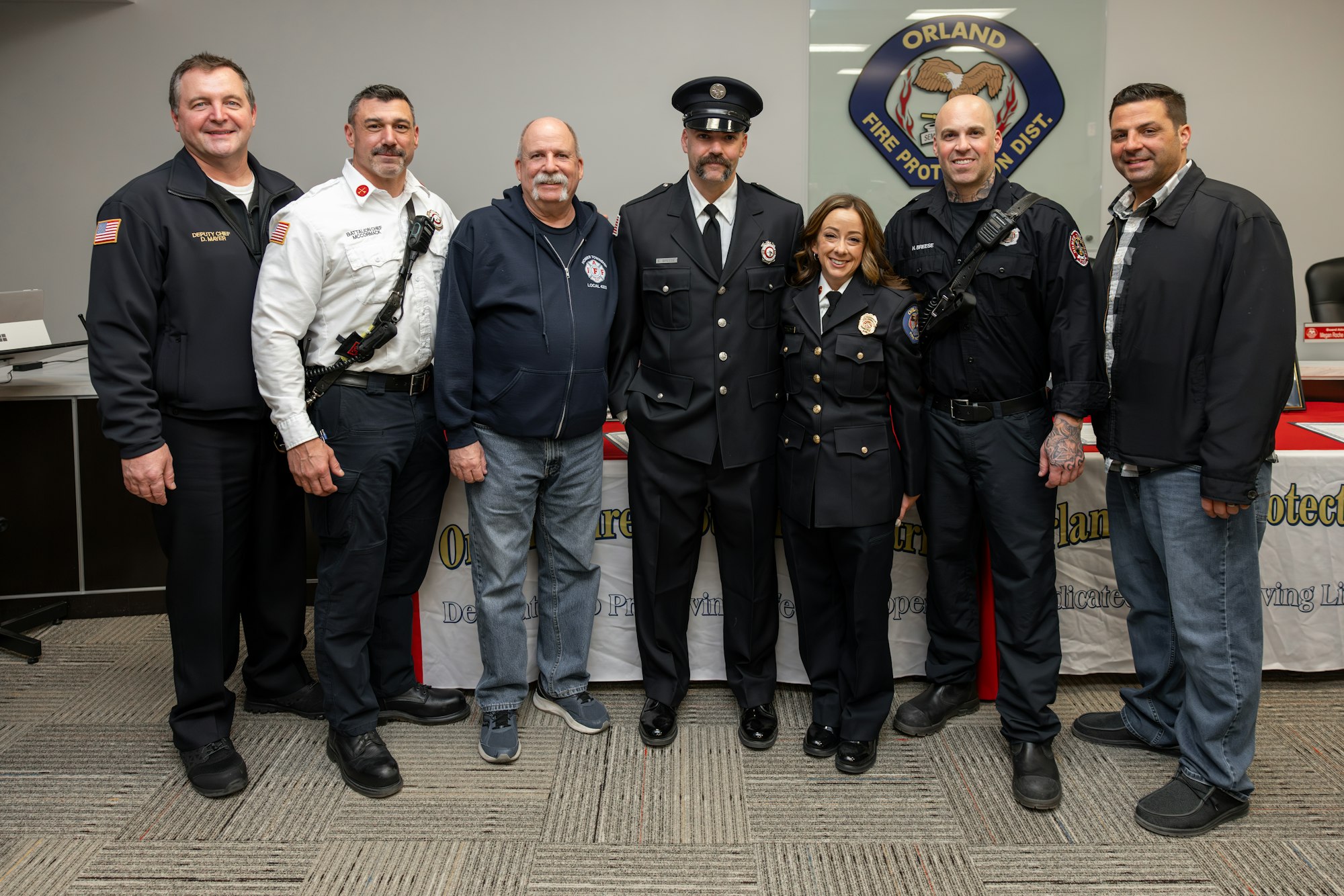 A group of seven individuals, including firefighters and support staff, posed together at a fire department event.