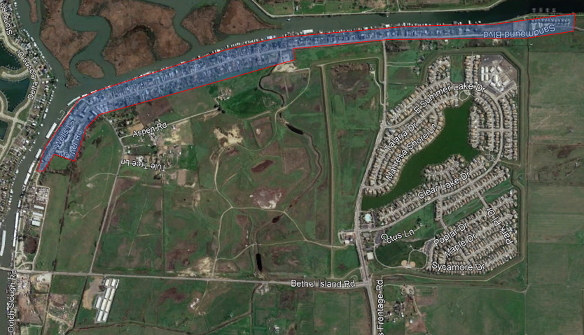 Aerial view of a residential area with streets, water bodies, and surrounding green fields.