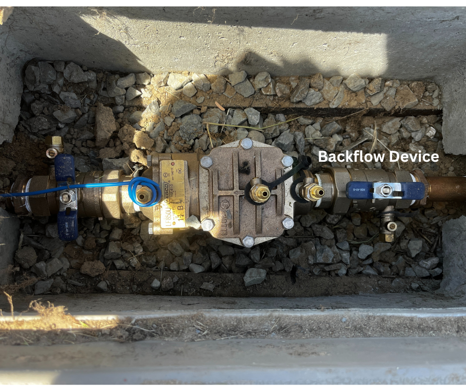 A backflow device installed underground with valves, surrounded by gravel.