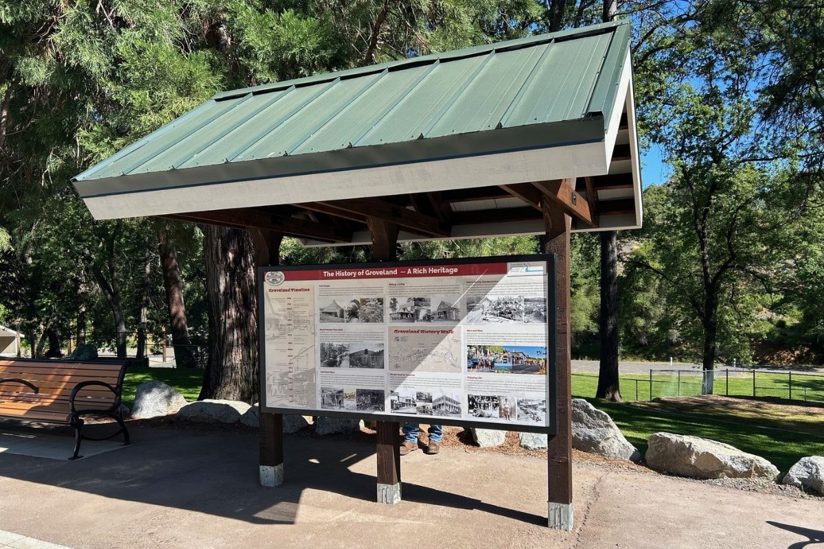 A sign in a park detailing the history of Groveland, featuring images and text about its heritage and past.