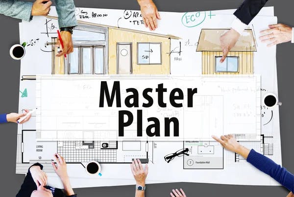 A group of people pointing at architectural blueprints labeled "Master Plan," depicting a house design.