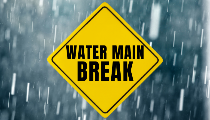 Yellow diamond sign reads "WATER MAIN BREAK" over a rainy background.