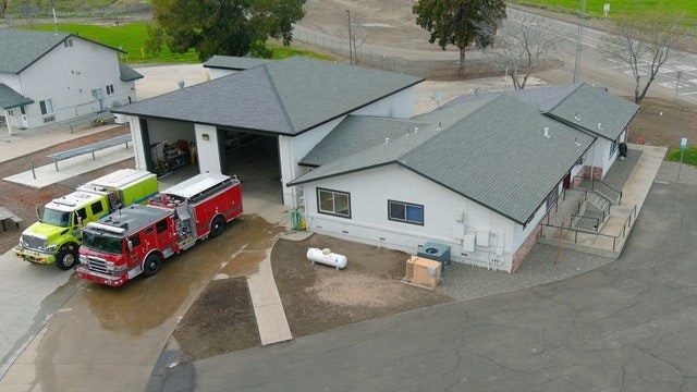 A fire station with two fire trucks parked outside.