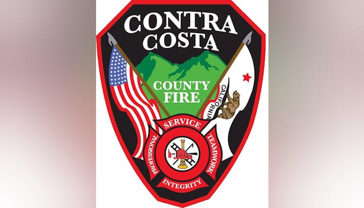 The image shows the emblem of Contra Costa County Fire, with a flag, mountains, a fire symbol, and a motto.