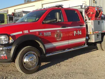 A red fire service pickup truck marked P-94 parked outside, during the day.