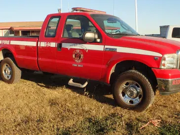 A red fire department pickup truck parked on grass.