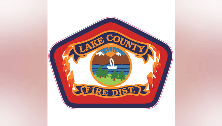 A badge/logo for Lake County Fire District featuring a lake, trees, and flames.