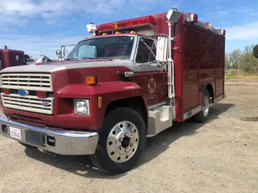 A red fire department rescue vehicle parked on a gravel lot.